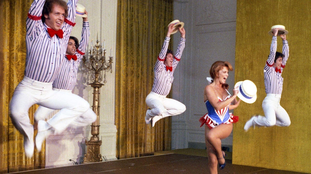 Ann-Margret performing with male dancers in the air wearing striped shirts and bow ties.