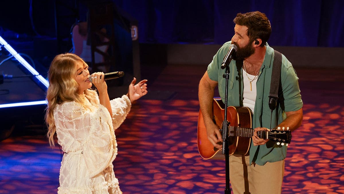 Anne Wilson e Jordan Davis se apresentando no palco do Ryman Auditorium em Nashville