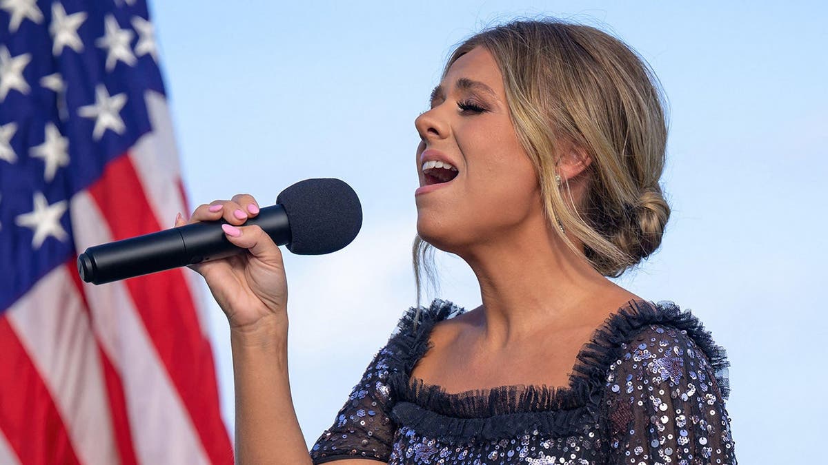 A artista country Anne Wilson cantando o hino nacional no evento do Kennedy Space Center
