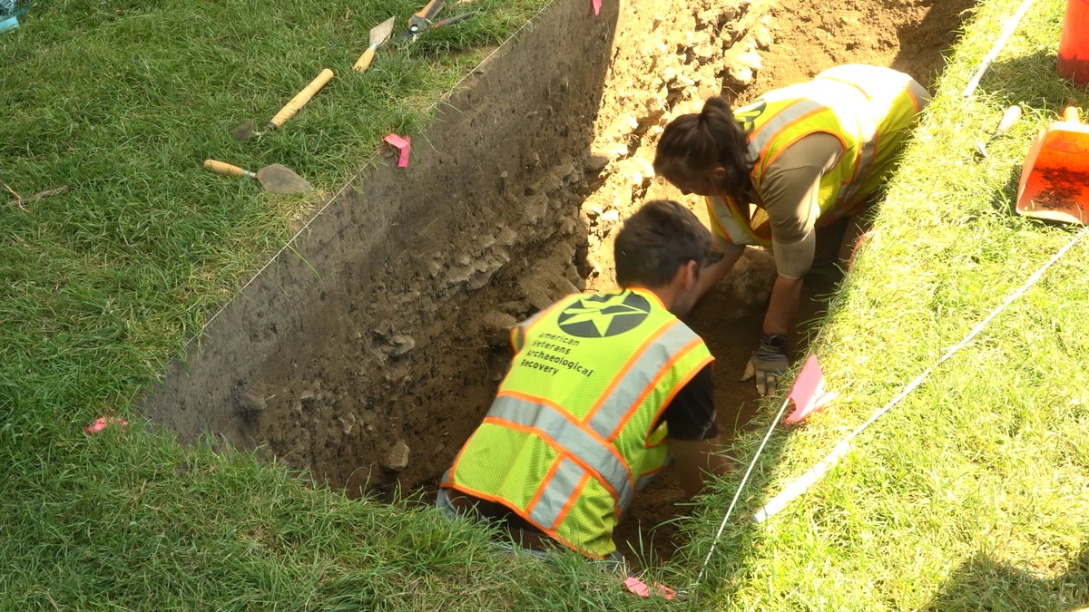 Archaeologists digging in a trench