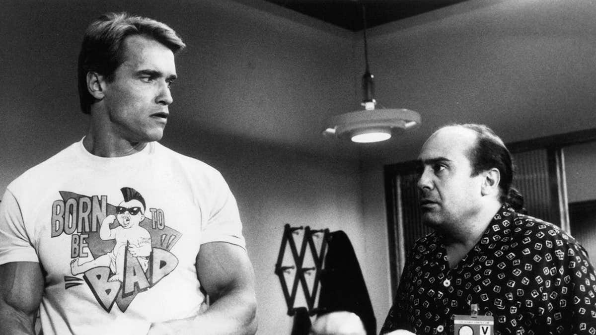 Arnold Schwarzenegger looking back at Danny DeVito in a film scene.