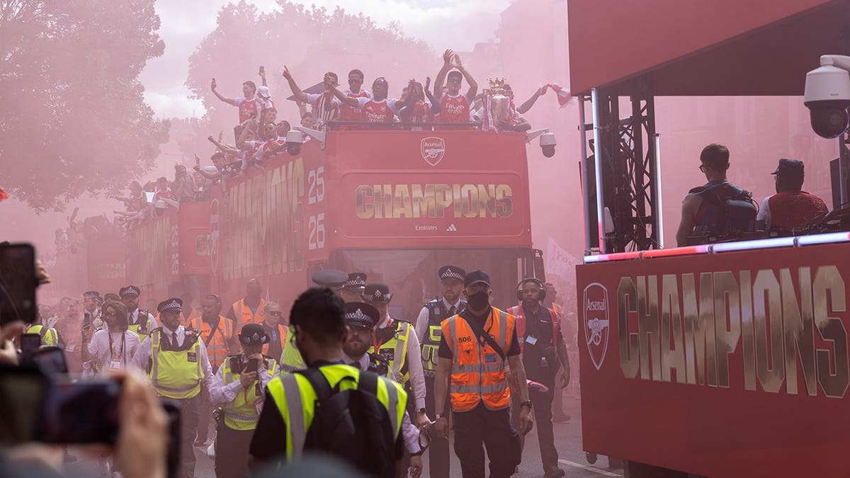 Arsenal players celebrating with Premier League trophy on open-top bus in London