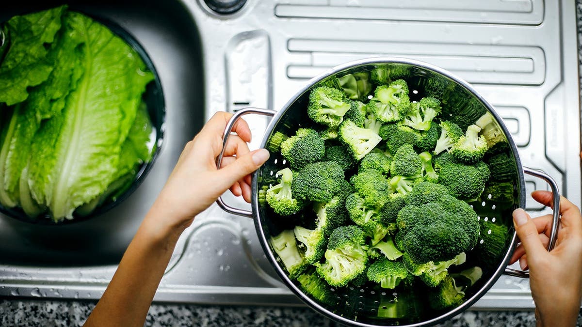 A personification prepares broccoli successful a kitchen.