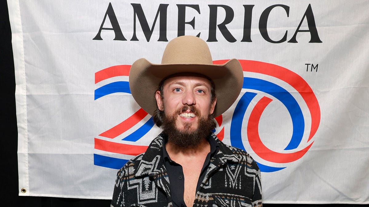 Chris Janson standing in front of an America Salutes You banner in Nashville, Tennessee