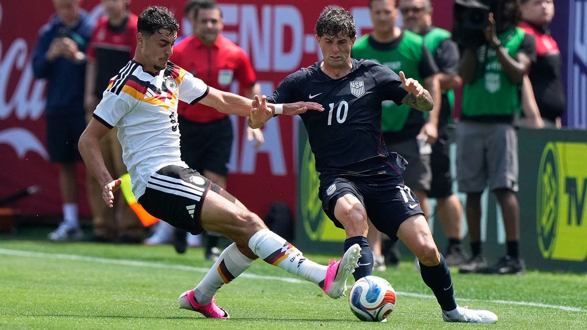 Germany midfielder Aleksandar Pavlović tackles the ball from United States forward Christian Pulisic in a soccer match