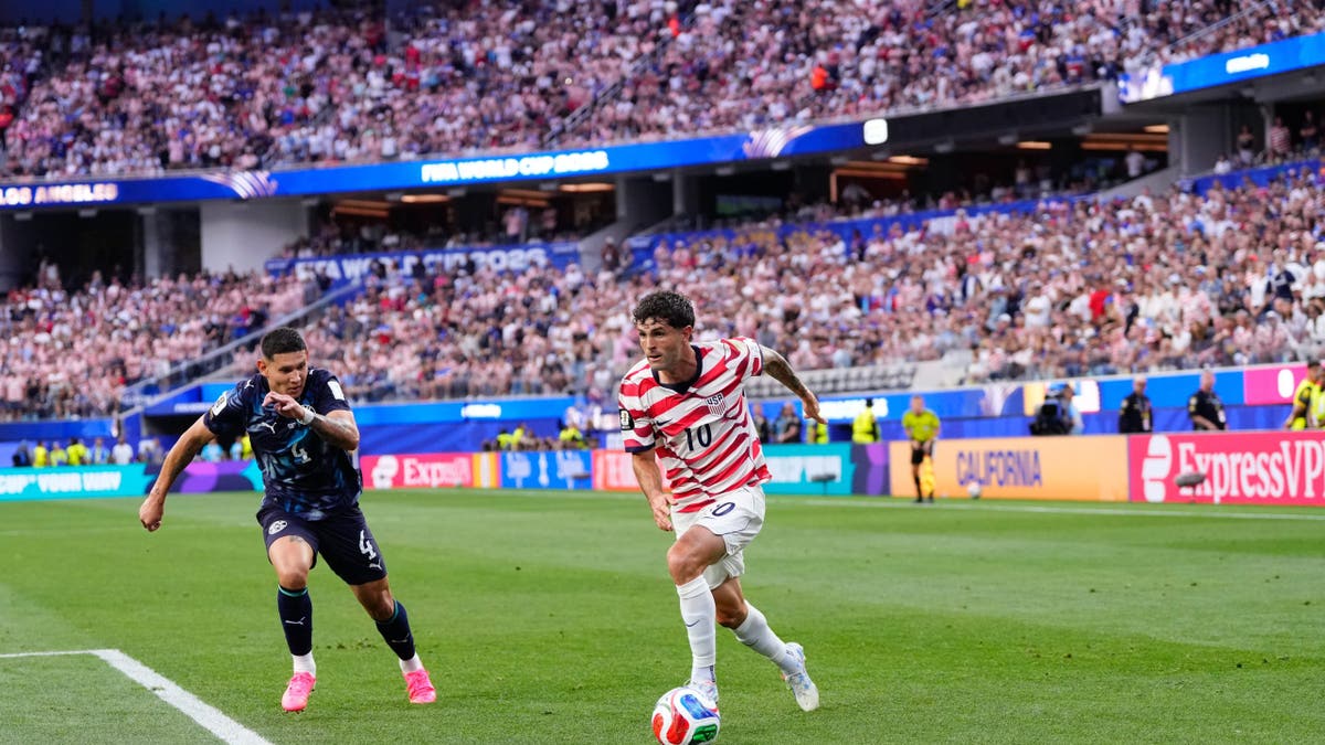 Christian Pulisic corriendo con el balón durante un partido de fútbol en el Los Stadium.