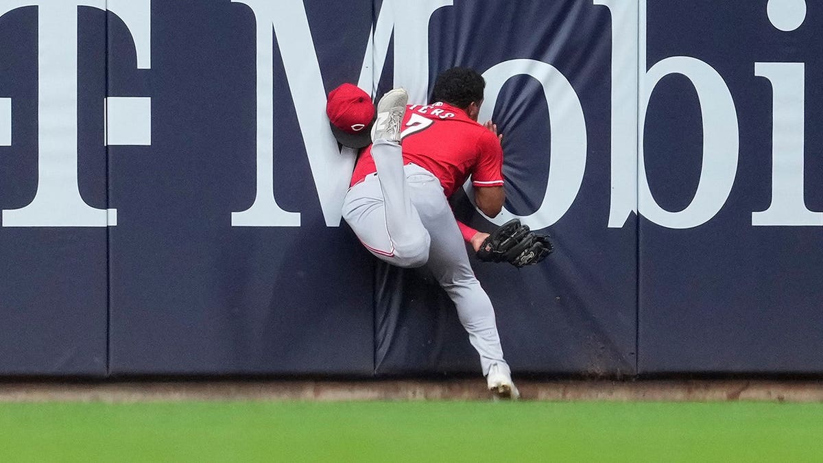 Cincinnati Reds' Dane Myers running into the wall after making a catch during a baseball game.