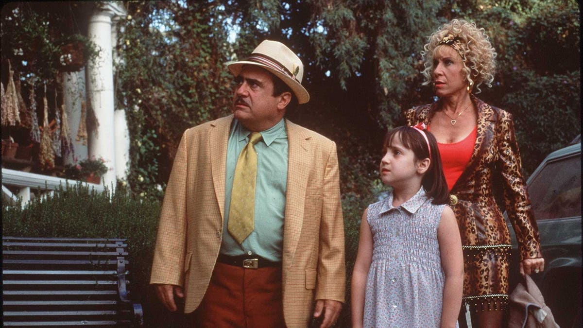 Danny DeVito and Rhea Perlman standing together with Mara Wilson in a scene from Matilda