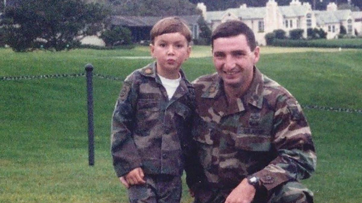 A father and son standing together smiling at the camera.