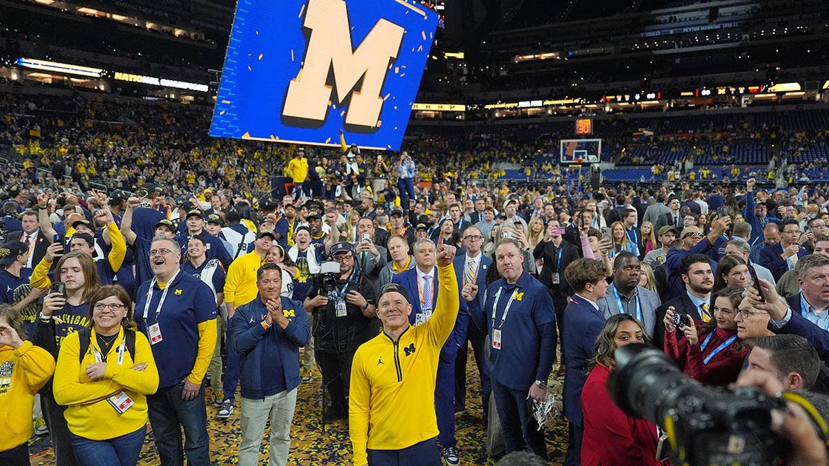 Hlavný tréner Michiganu Dusty May oslavuje na basketbalovom ihrisku.