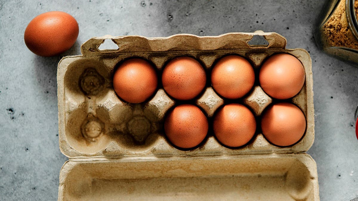 A carton of brown eggs sits on a table.