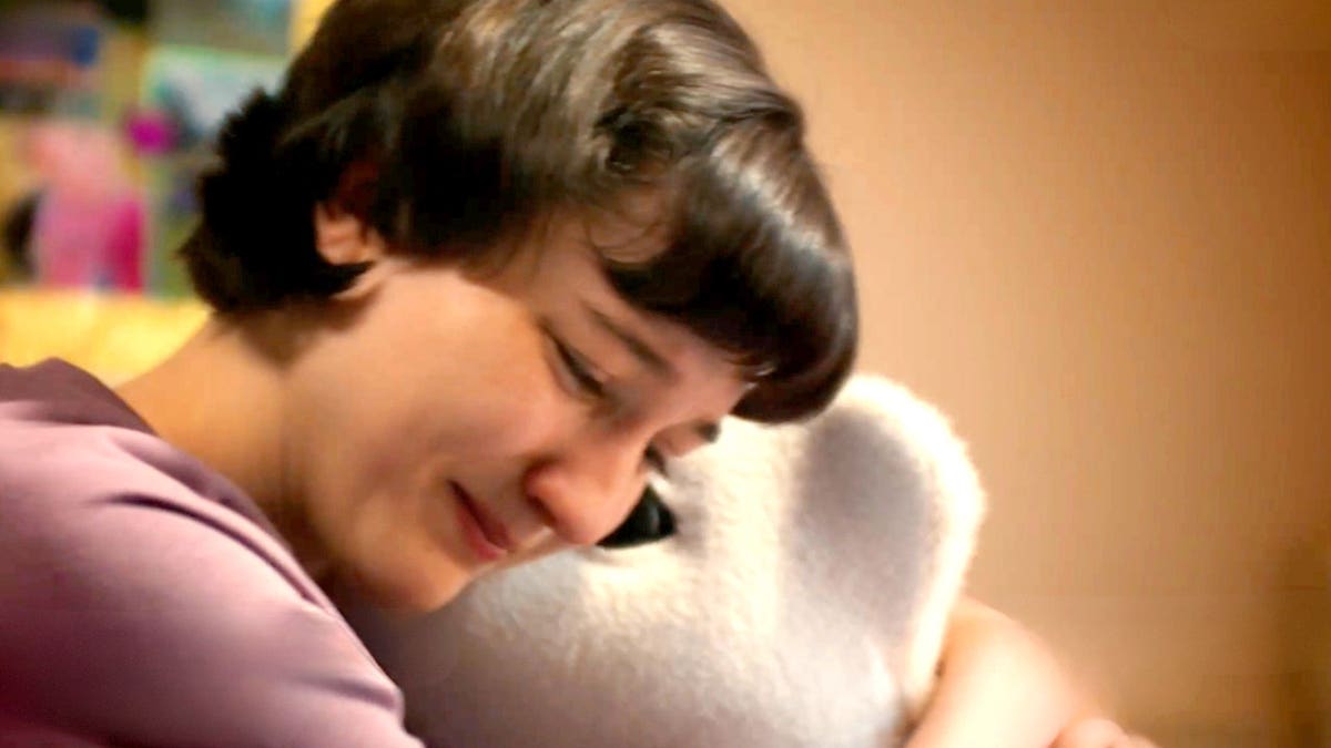 A woman hugs a robotic pet.