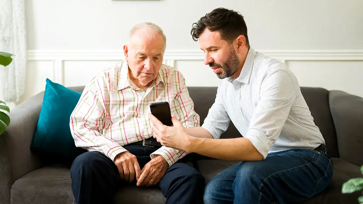 A man shows his father how to do something on a smartphone.