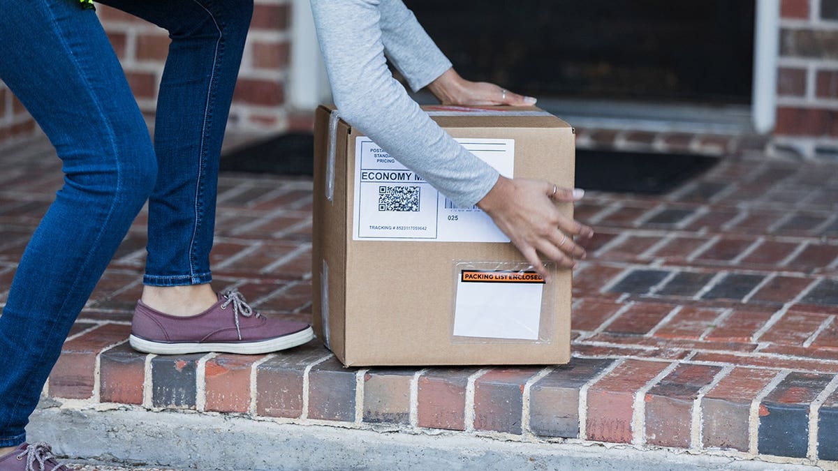 Female delivery person handling a package at a residence