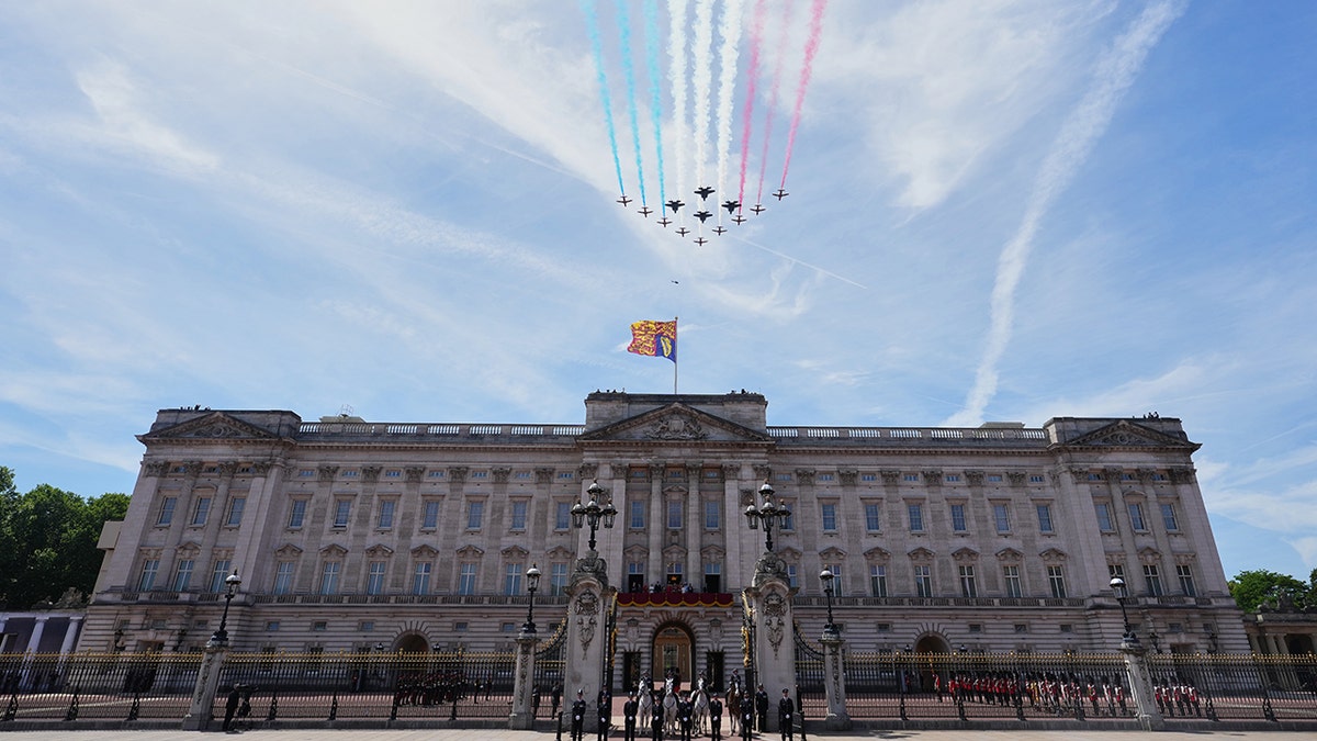 Royal Air Force aircraft flying over Buckingham Palace as members of the royal family watch from a balcony.