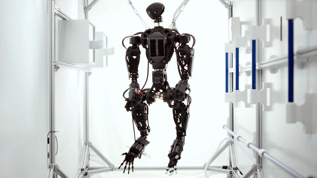 A four-armed robot hangs in a white room.