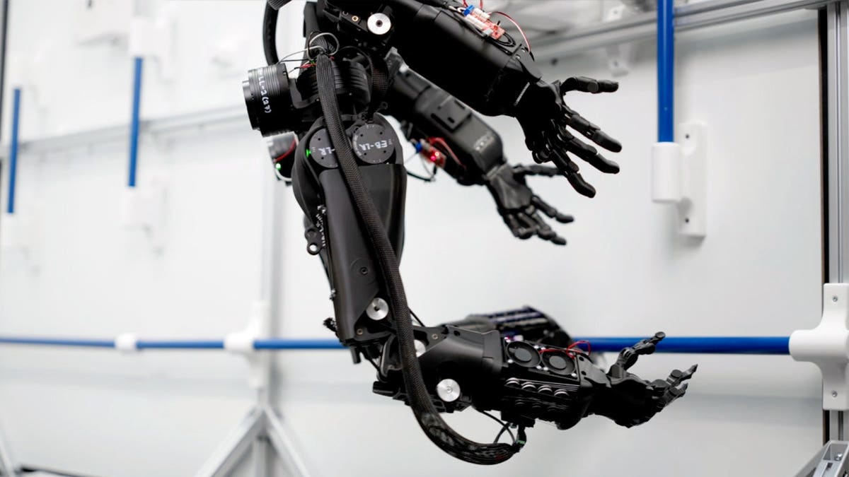 Four robotic arms stretch out toward a wall.
