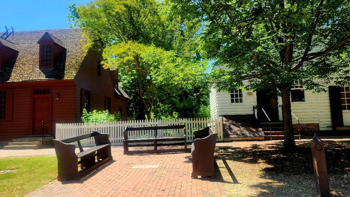 Wooden benches face each other on a street in Colonial Williamsburg.