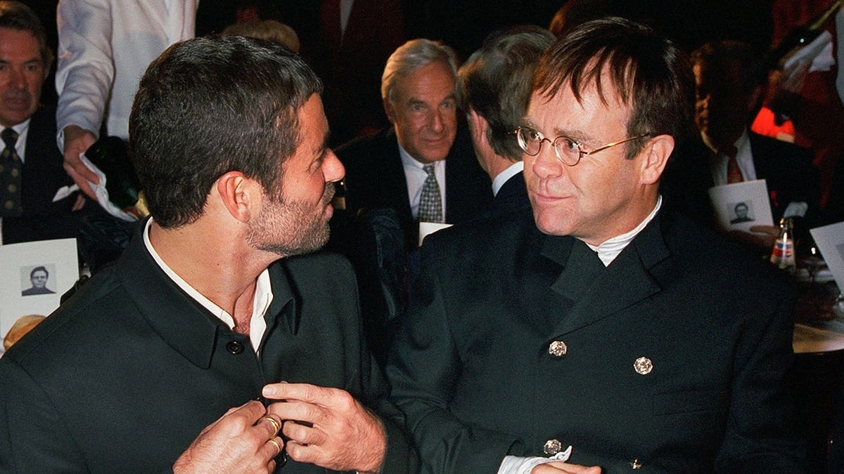 George Michael and Elton John standing together at a gala dinner event.