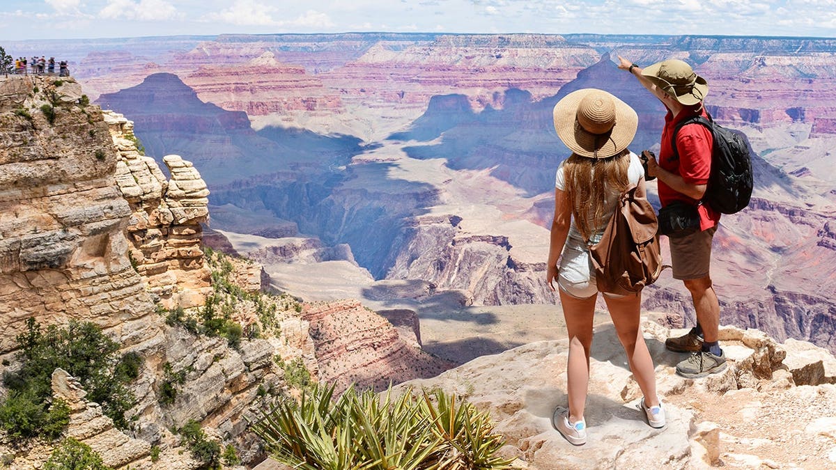 Couple standing on top of a mountain overlooking the Colorado River at Grand Canyon National Park