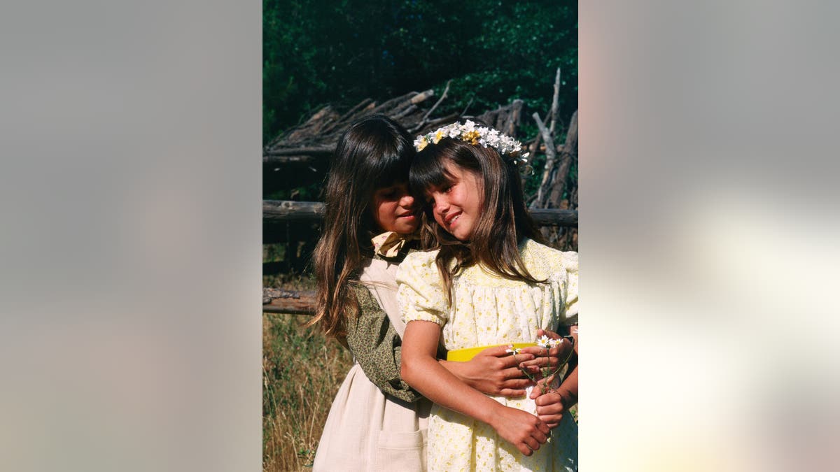 Lindsay Greenbush and Sidney Greenbush standing side by side in costume on set.