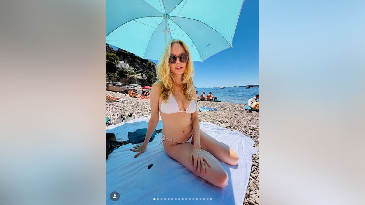 Heather Graham in a white bikini on the shore of the beach in France.