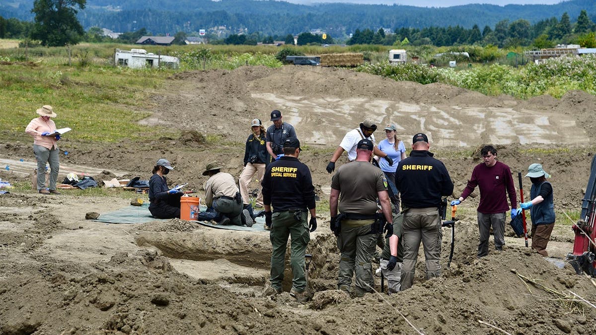 photo shows several investigators standing over an excavation site