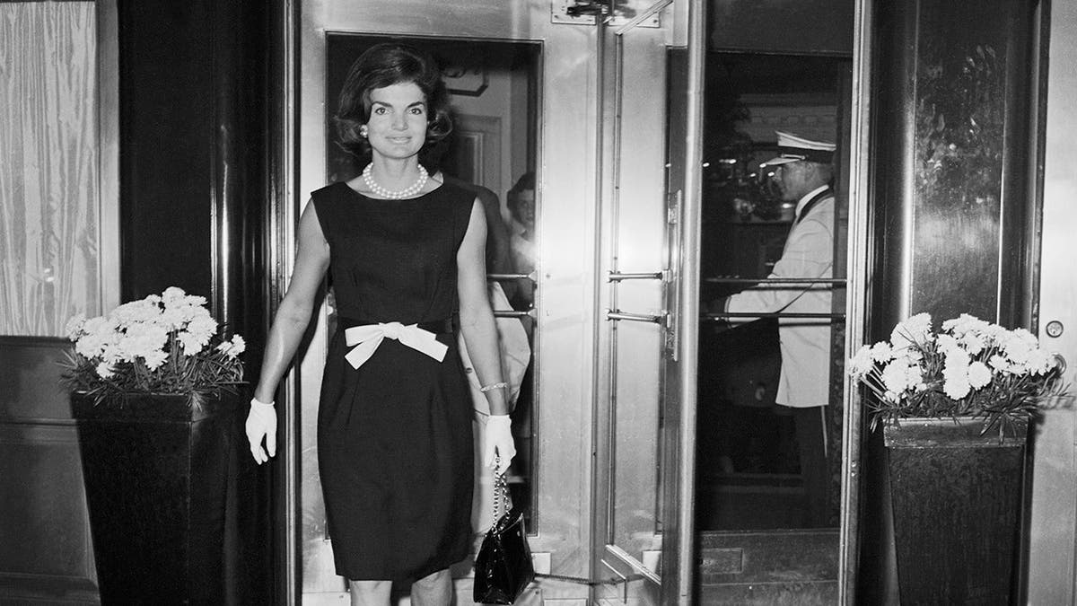 Mrs. Jacqueline Kennedy wearing a bow-at-the-waist dress leaving the Hotel Carlyle.
