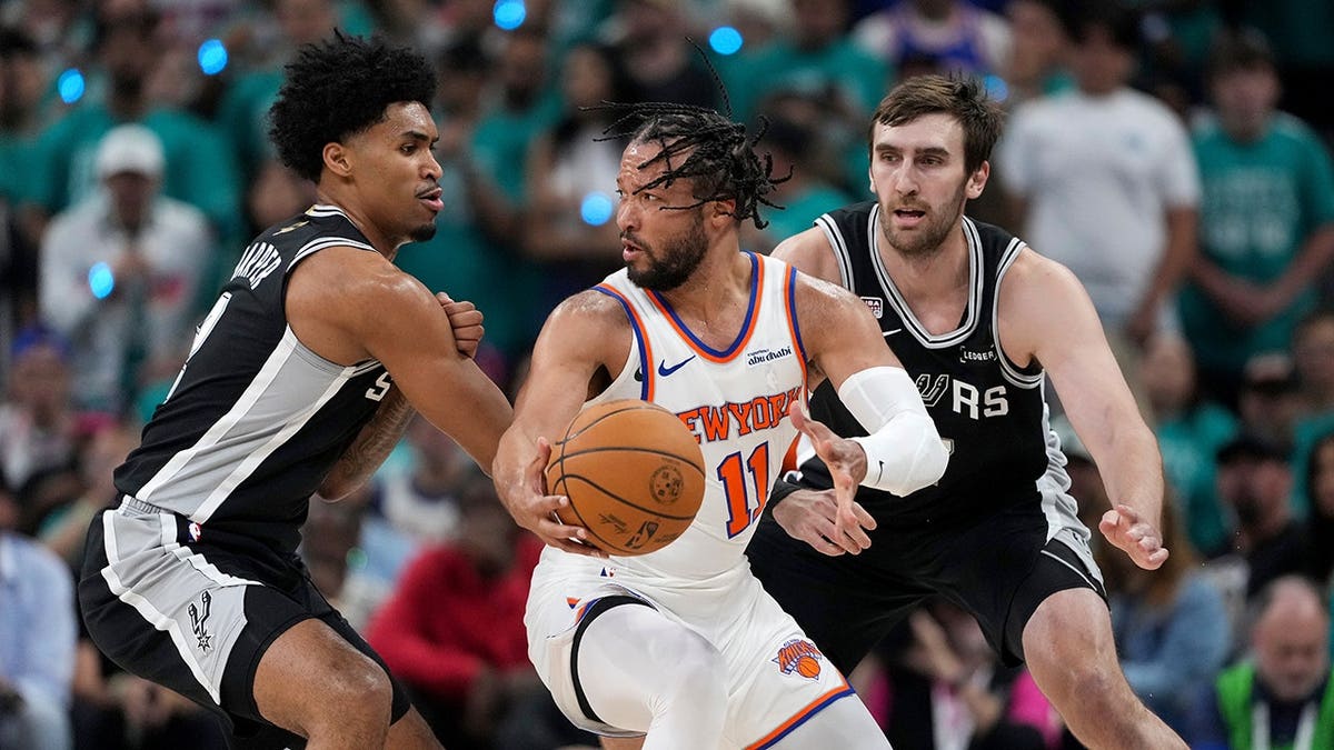 El base de los New York Knicks, Jalen Brunson, hace un giro con el balón mientras el base de los San Antonio Spurs, Dylan Harper, le defiende