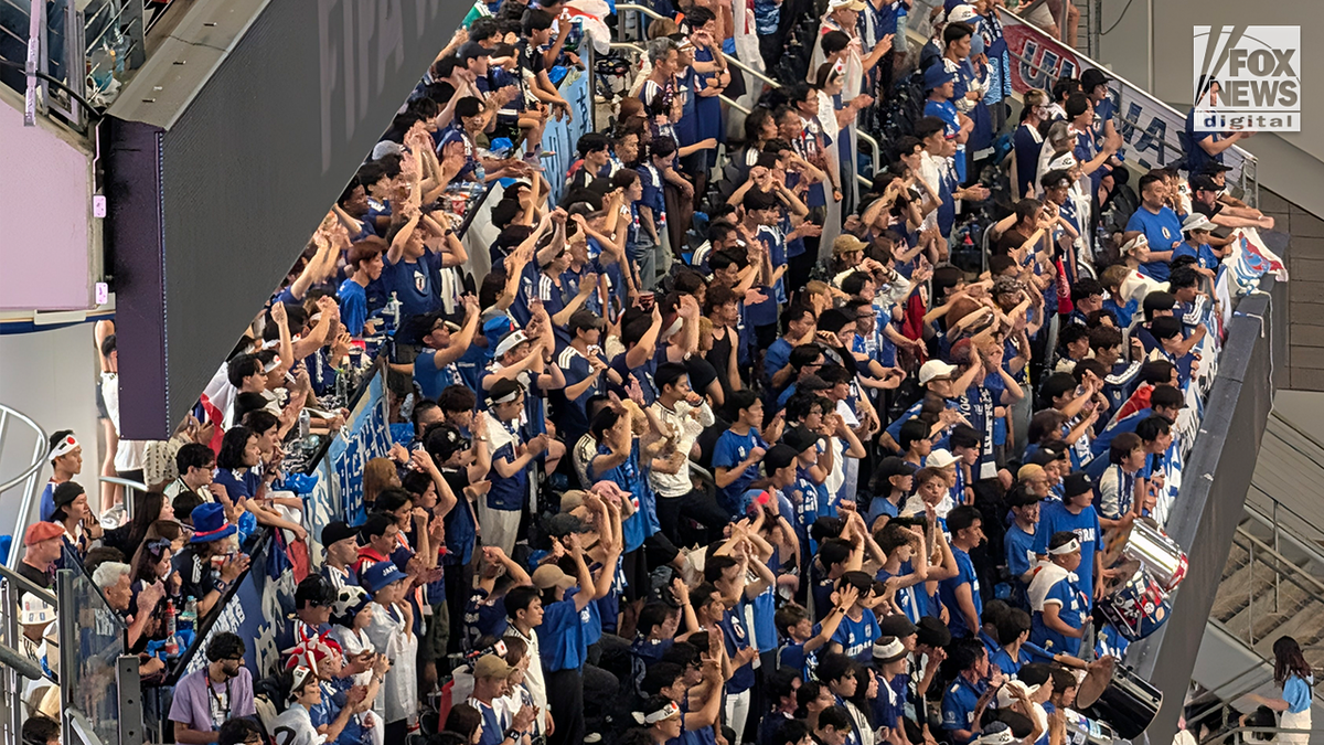 Japan nationalist squad supporters dressed successful bluish cheer and raise their arms from a packed stadium conception during a FIFA World Cup match.