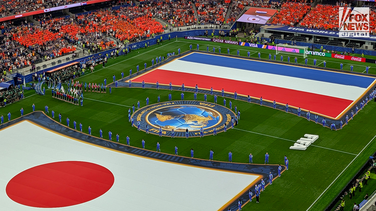 Large Japanese and Netherlands nationalist flags are displayed crossed nan section during a FIFA World Cup pre-match ceremonial arsenic teams and officials statement nan transportation successful a packed stadium.