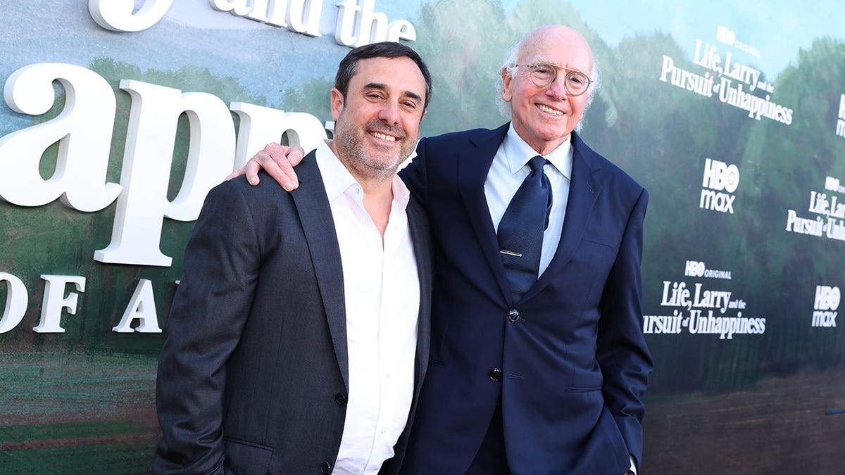 Jeff Schaffer and Larry David standing together on a red carpet at a premiere event