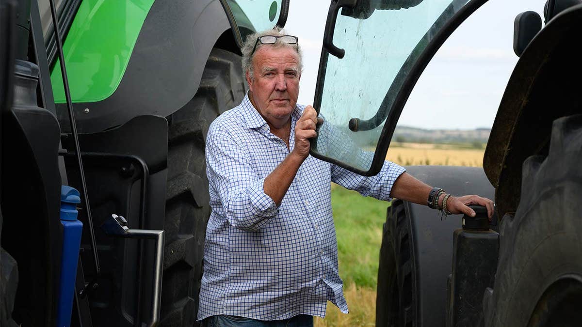 Jeremy Clarkson stands between two tractors