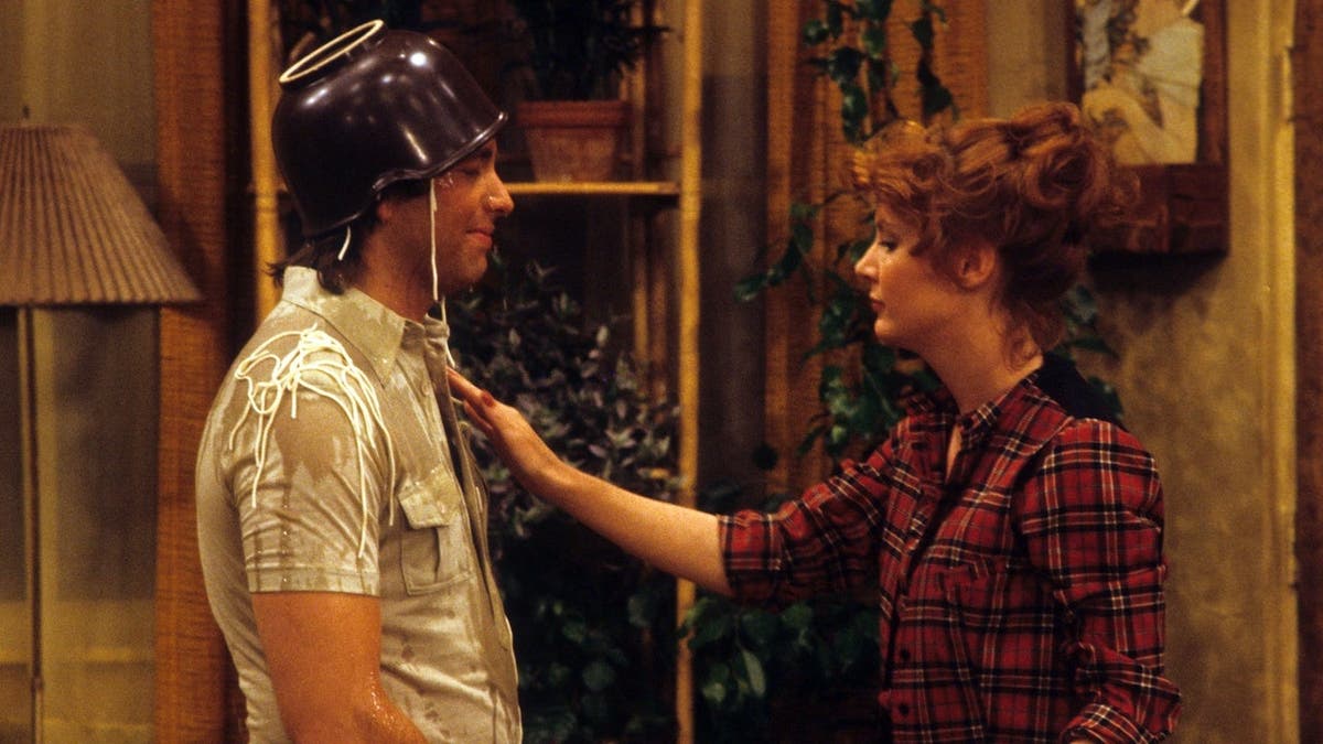 John Ritter and Anne Scheden standing together in a scene from Three's Company.