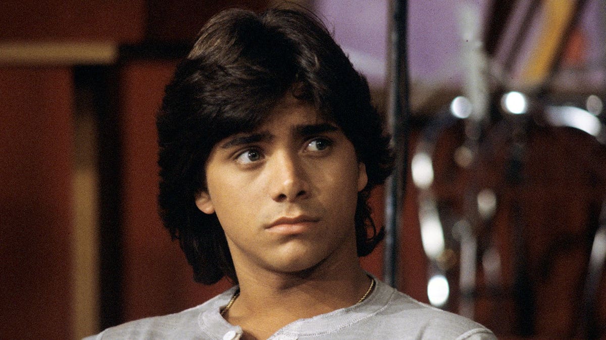 John Stamos standing in a scene from General Hospital.