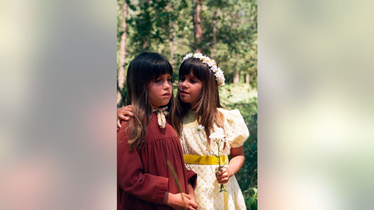 Lindsay Greenbush as Carrie Ingalls and Sidney Greenbush as Alyssa standing together in a scene from Little House on the Prairie