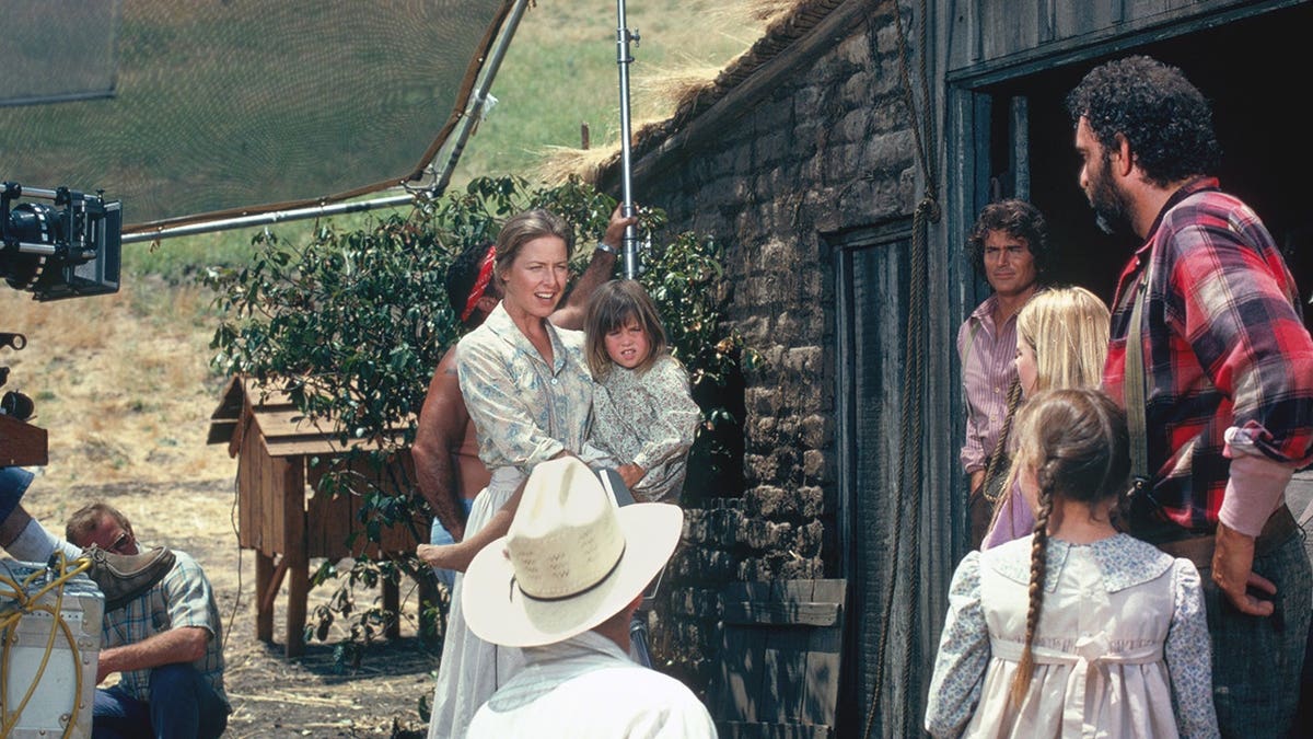 Karen Grassle as Caroline Ingalls, Lindsay Greenbush as Carrie Ingalls, Michael Landon as Charles Ingalls, Victor French as Isaiah Edwards standing together