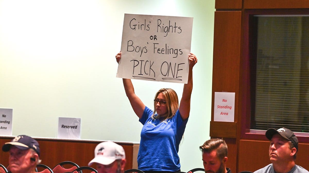 A mother holds up a sign reading