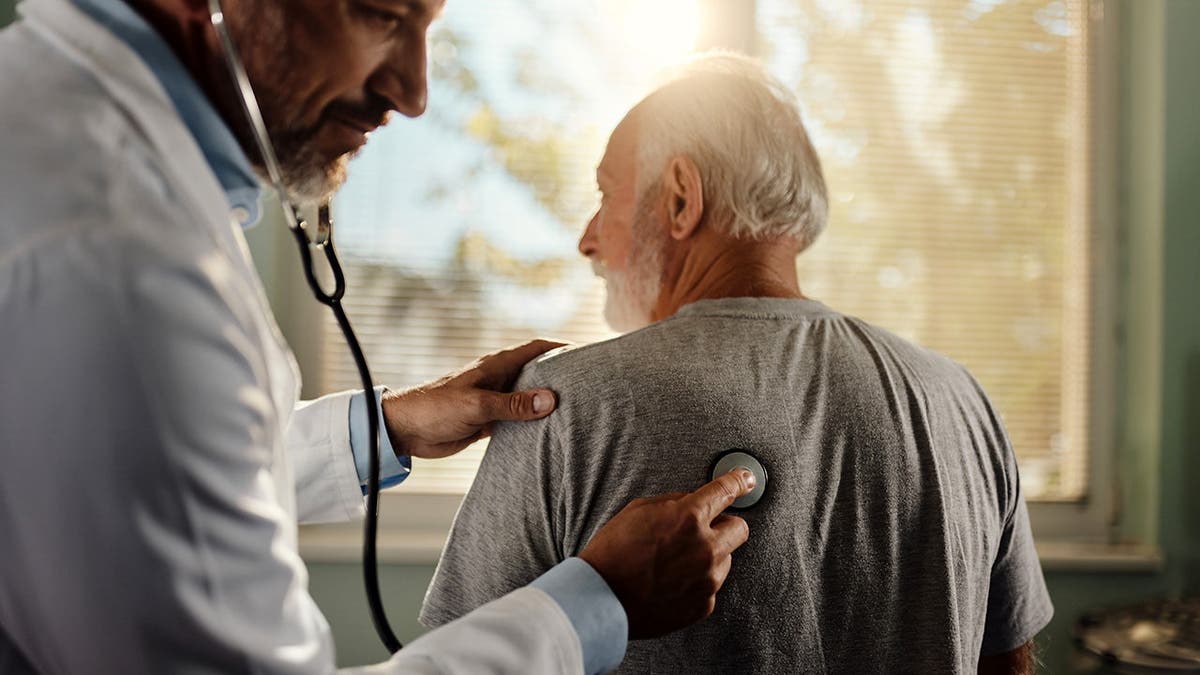A expert listens to a man's lungs.