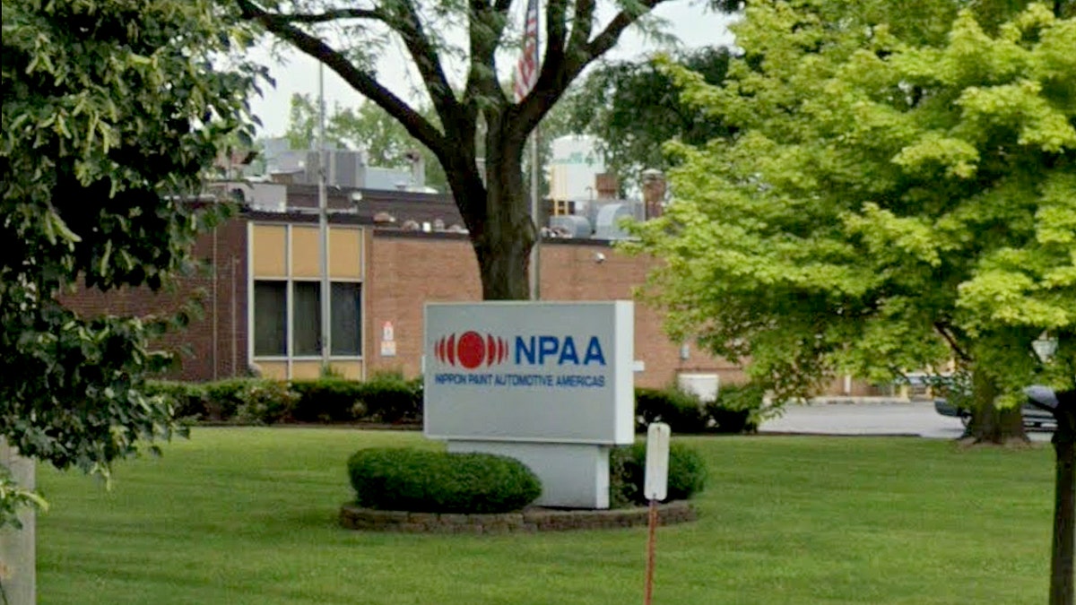 Street view of an industrial building in Lansing, Illinois, with a parking lot containing numerous vehicles parked outside the facility.