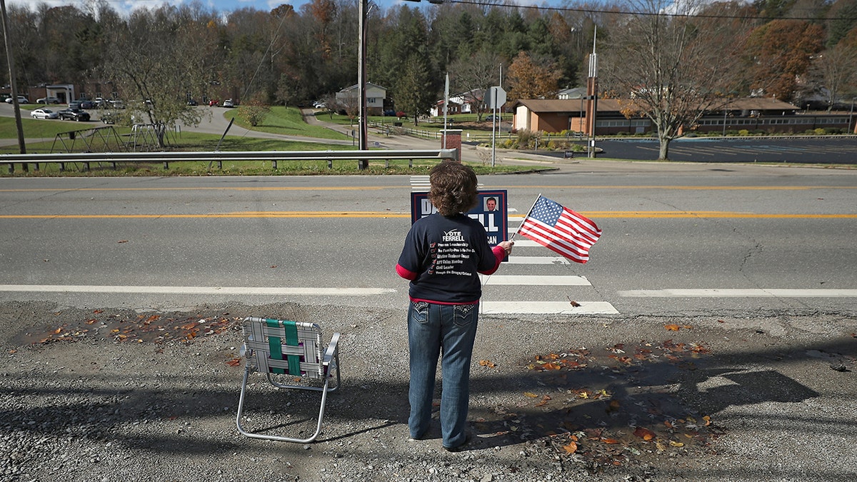 Pauline Monk stands by the side of the road campaigning for her son.
