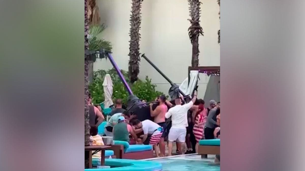 Guests and staff lift a collapsed metal cabana frame near the pool deck at the Seminole Hard Rock Hotel & Casino.