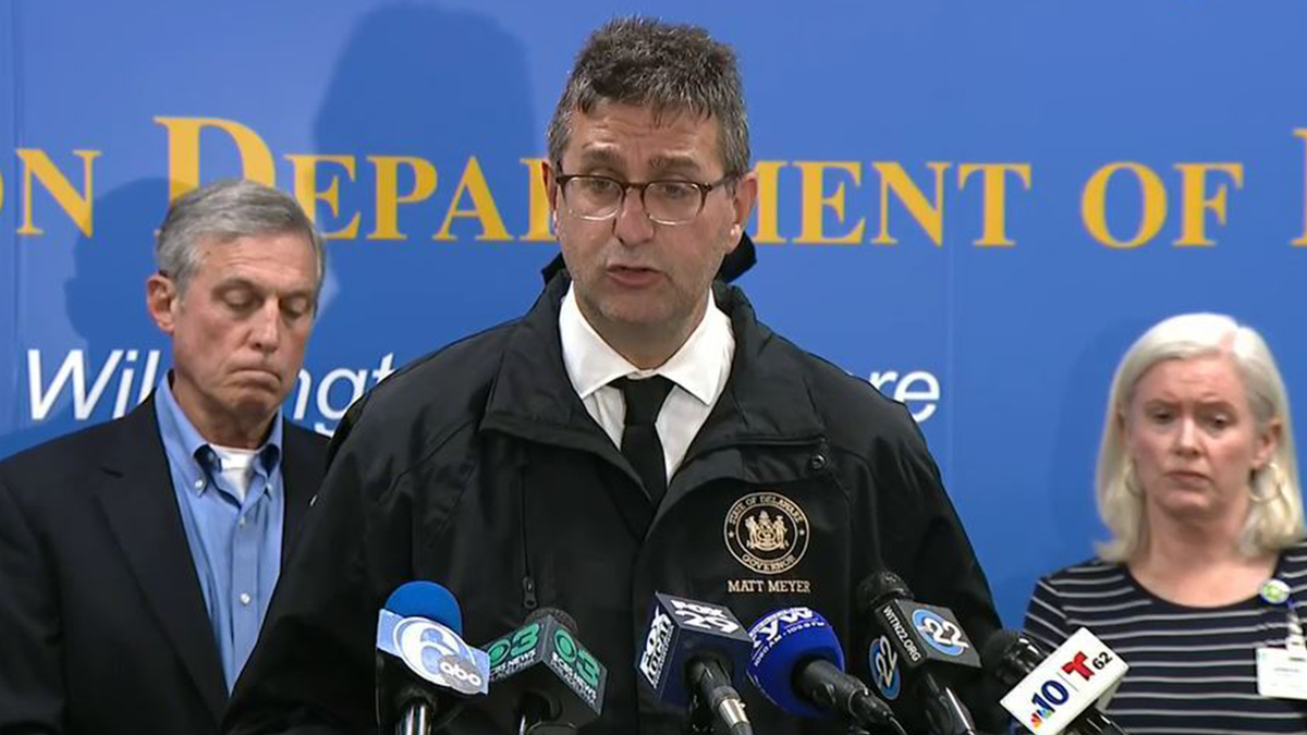 Delaware Gov. Matt Meyer speaks at a news conference, standing at a podium with multiple microphones and officials behind him.