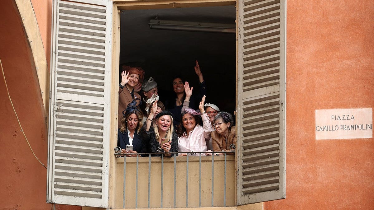 Women gesture from a window in Reggio Emilia, Italy, ahead of Princess Catherine's arrival