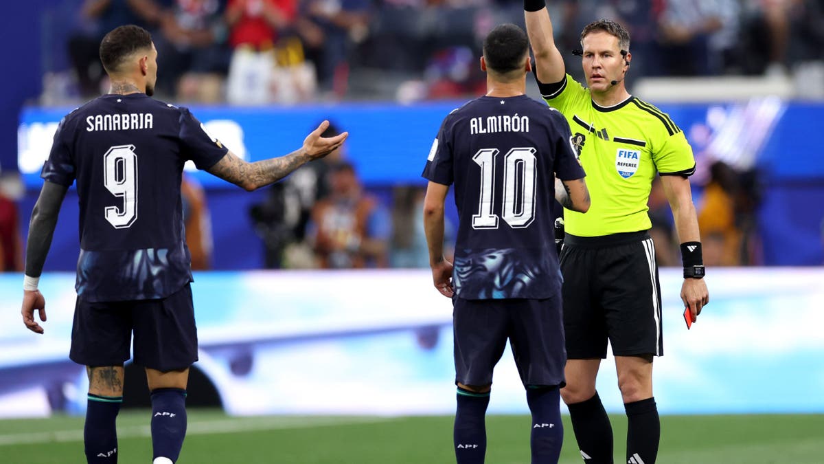 Referee Danny Makkelie showing a yellow card to Miguel Almiron on a soccer field