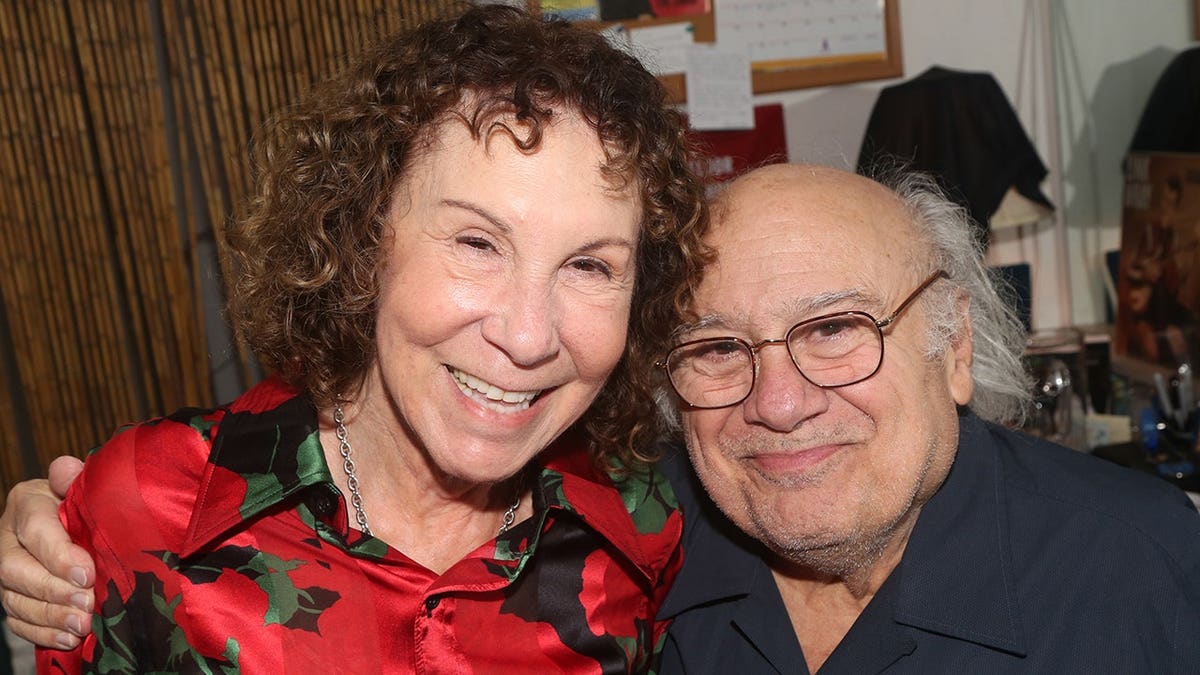 Rhea Perlman and Danny DeVito posing backstage at a Broadway theater