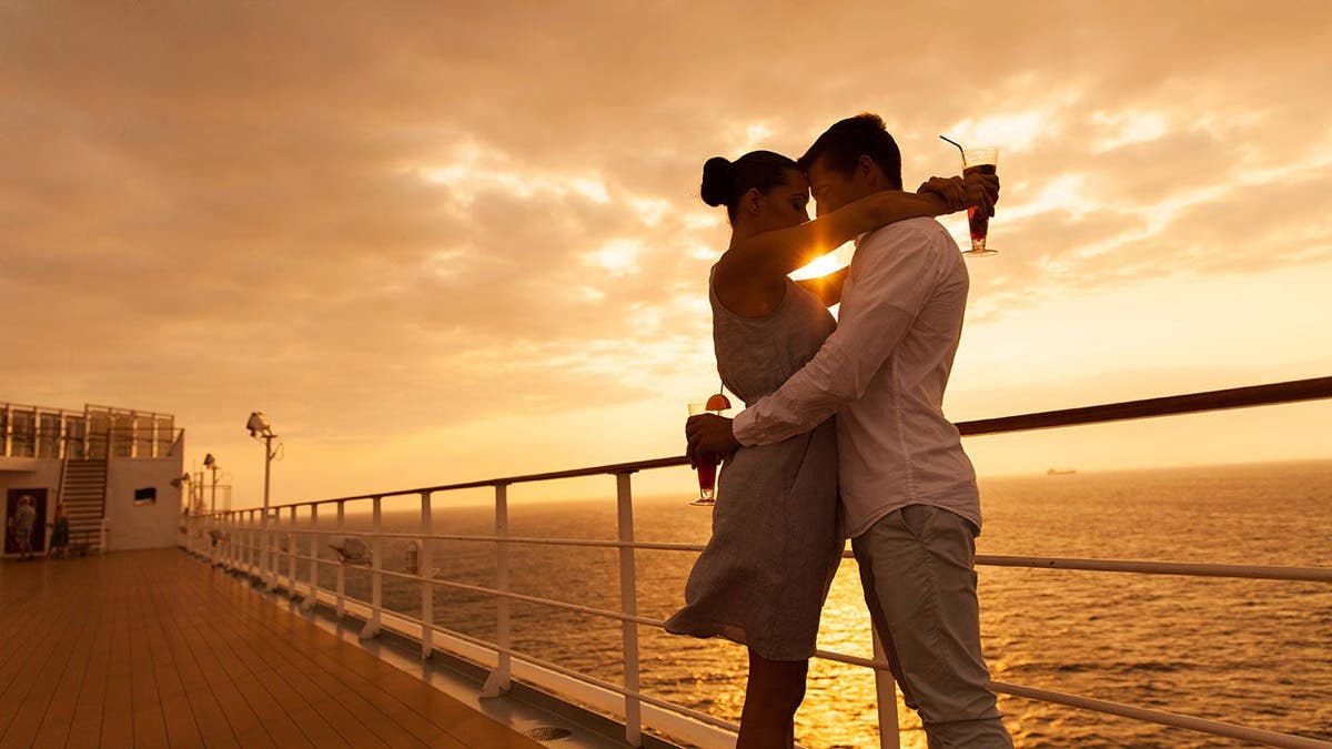 Romantic couple hugging with eyes closed on a cruise ship at sunset