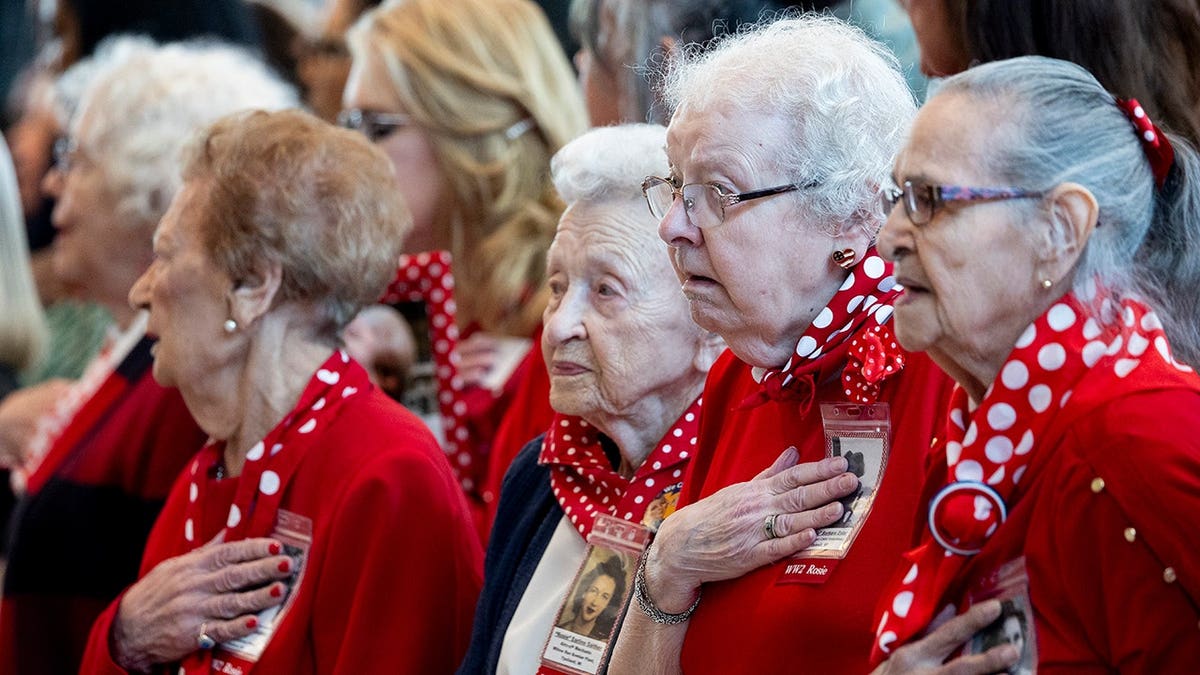 Rosie the Riveter women holding hands over hearts during National Anthem at U.S. Capitol