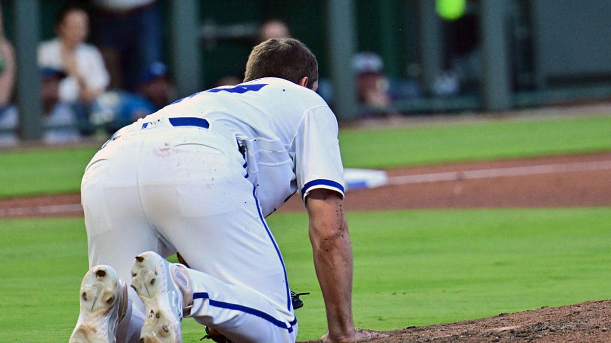Kansas City Royals pitcher Seth Lugo falls to the ground after being hit in the forehead by a batted ball