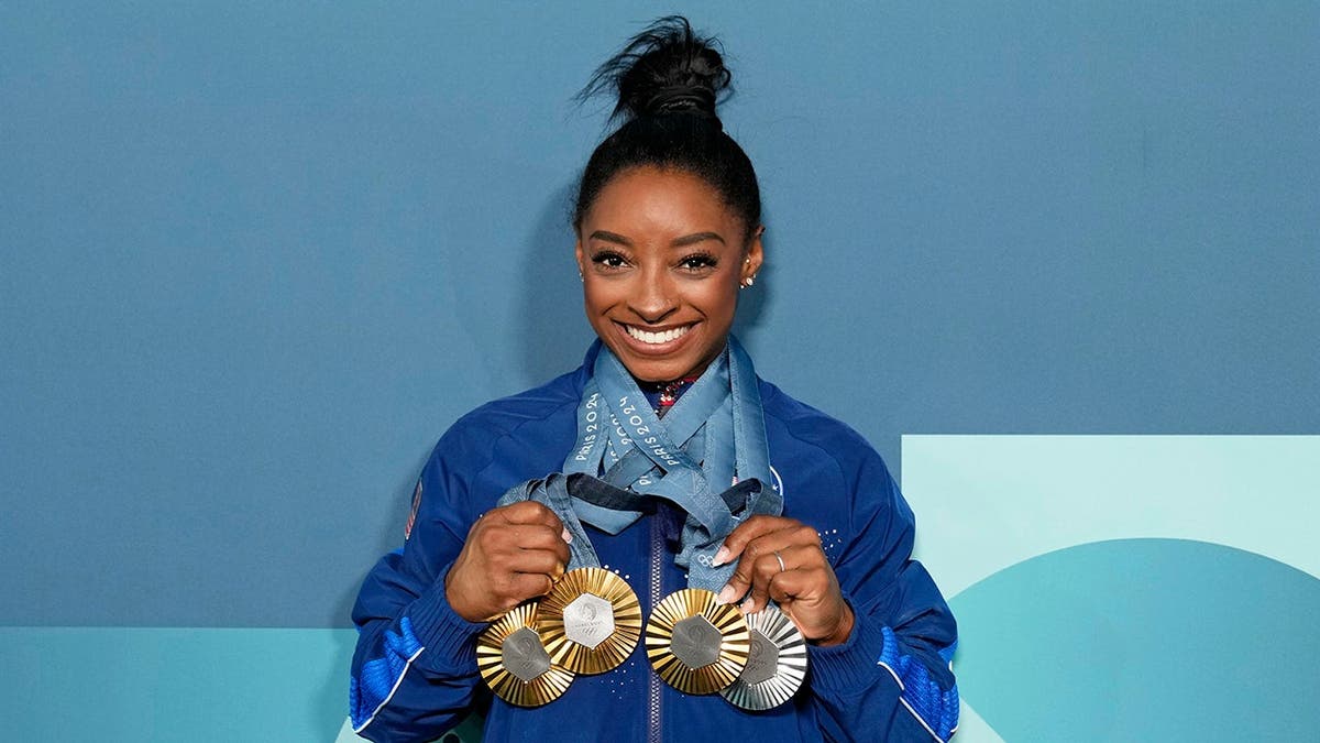 Simone Biles posing with three gold and one silver medal in Paris, France.